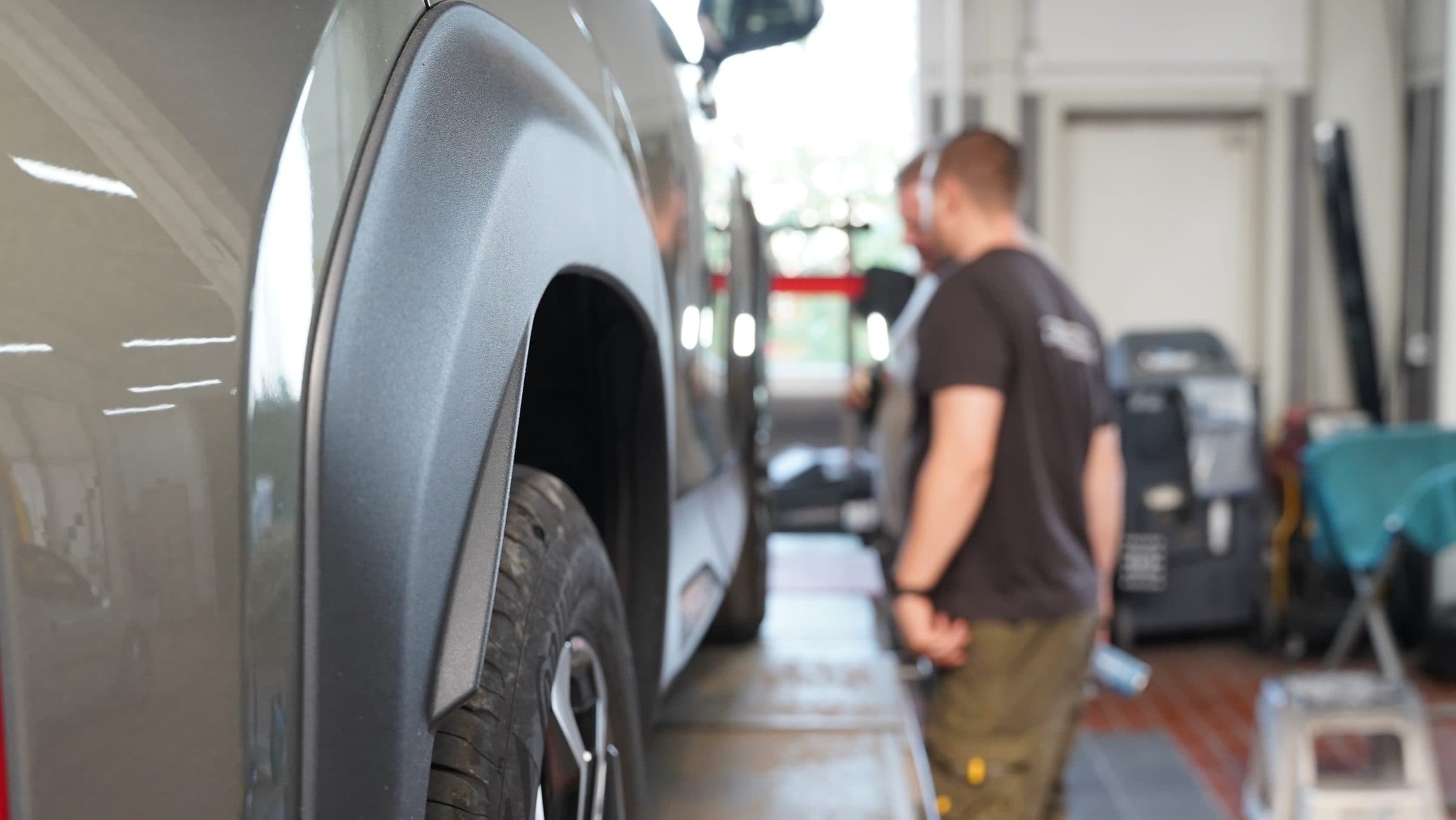 Mitarbeiter begutachten ein Fahrzeug in der Werkstatt von A. Schäfer in Neu-Anspach
